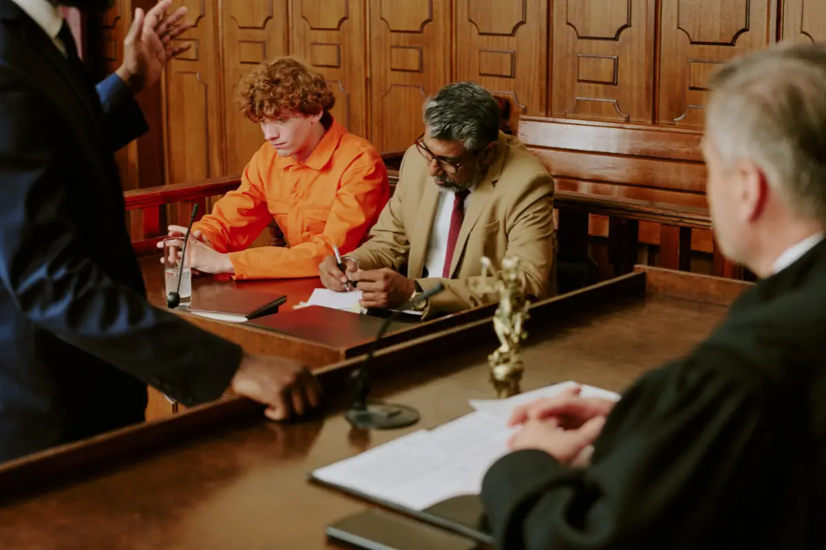 Defense attorney reviewing case files with a client in an orange jumpsuit at a court table, representing Maryland drug charges and defenses