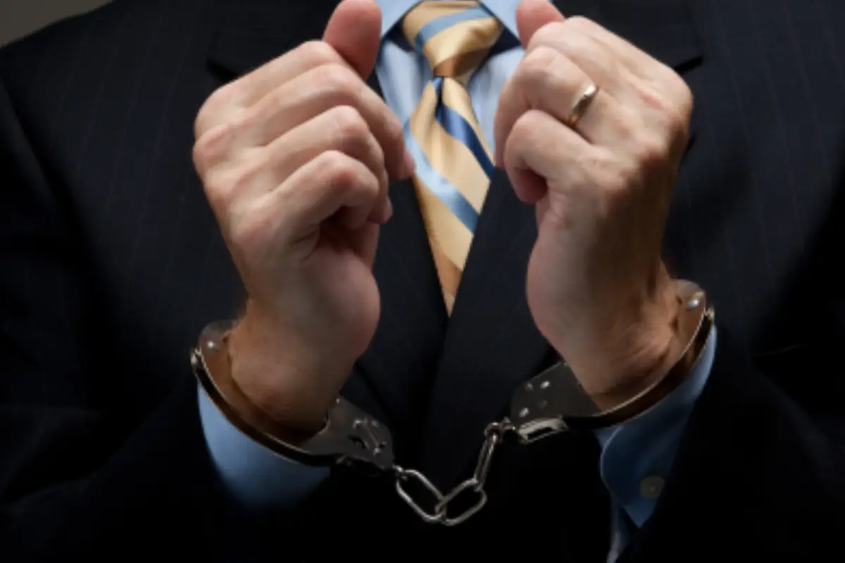 Handcuffed hands of a man in a business suit representing drug possession charges in Montgomery County